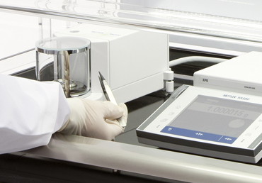 Analyst working with tweezers on a ST1 laboratory balance enclosure from Containment Technology Services