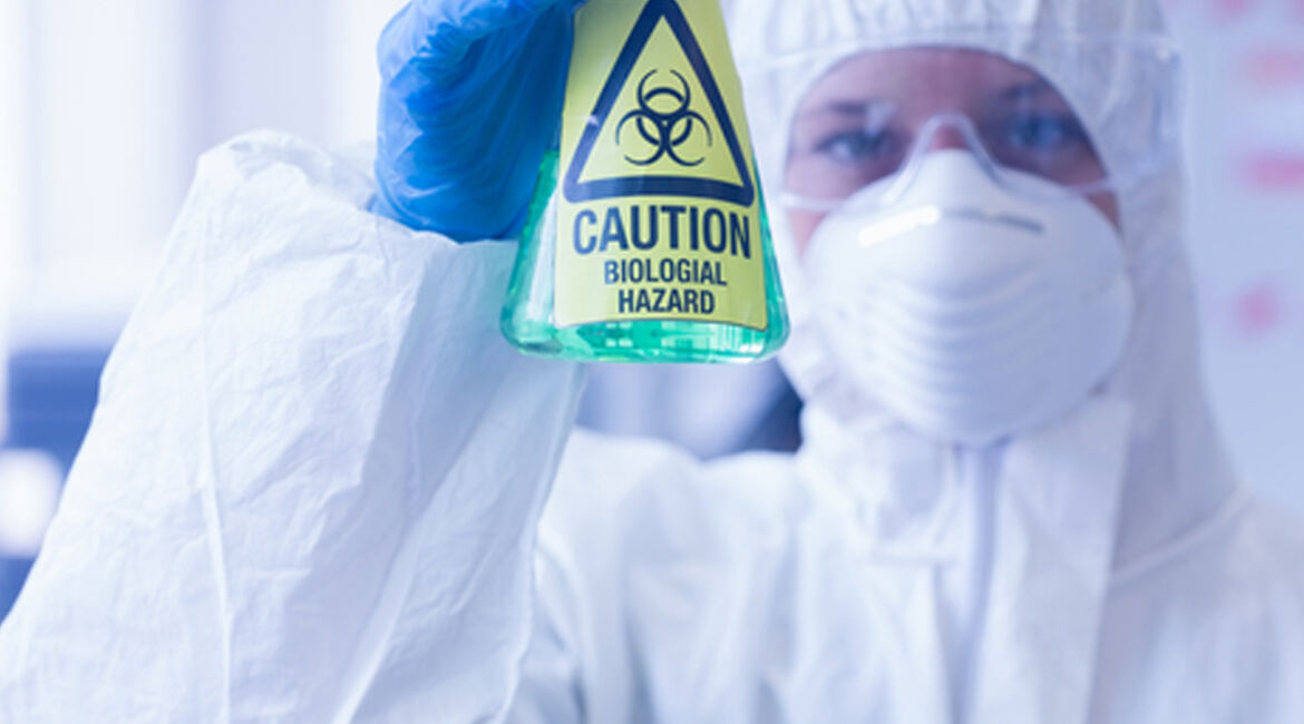 Laboratory analyst holding a biohazard in a bottle with a green liquid